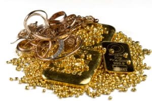 A pile of gold bars, gold jewelry and gold granules. Isolated on white background. Selective focus.